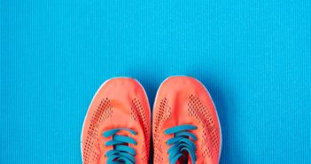 Orange Laufschuhe mit Schnürsenkeln auf blauen Grund